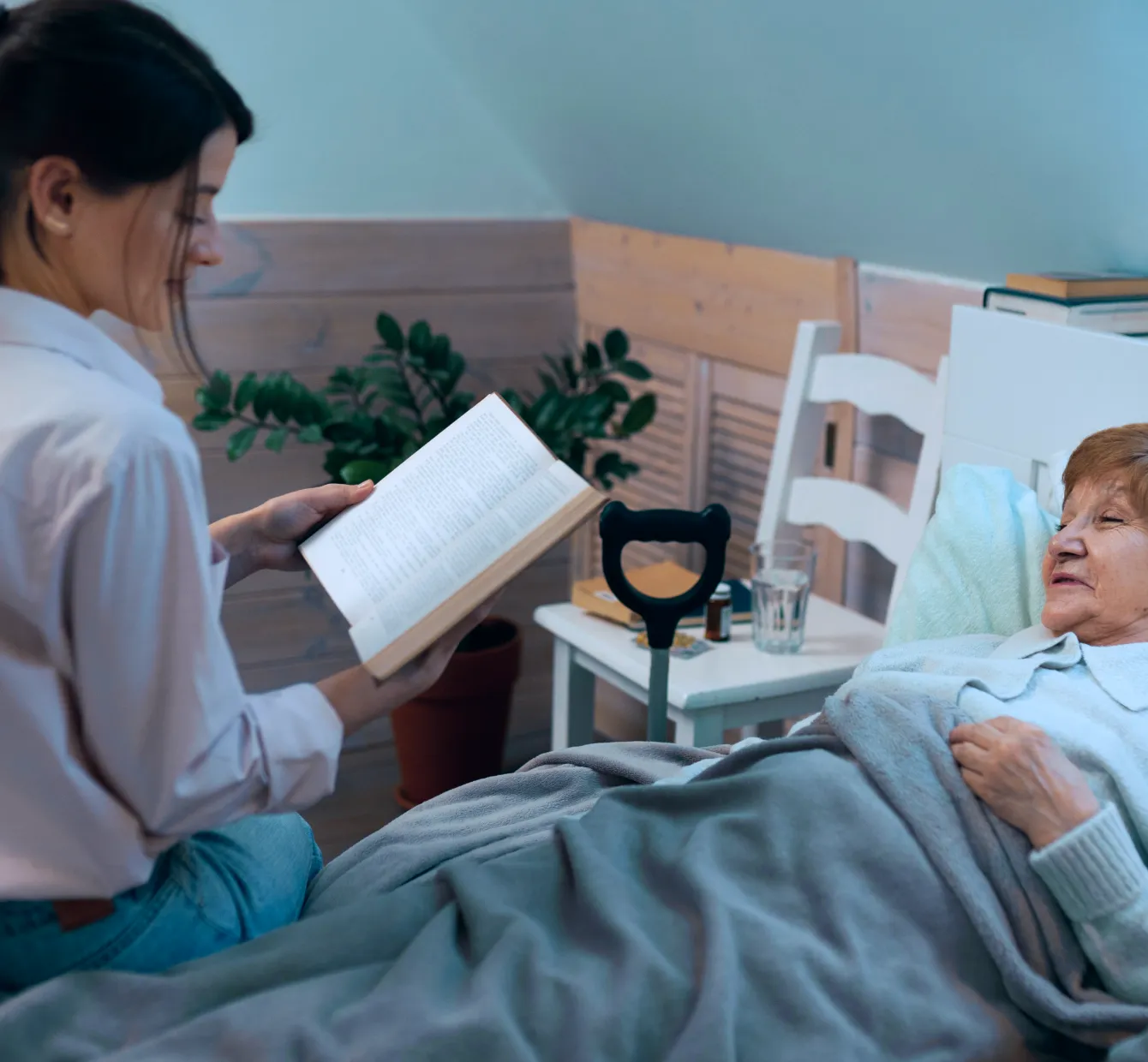 Night care professional reading with a client in bed